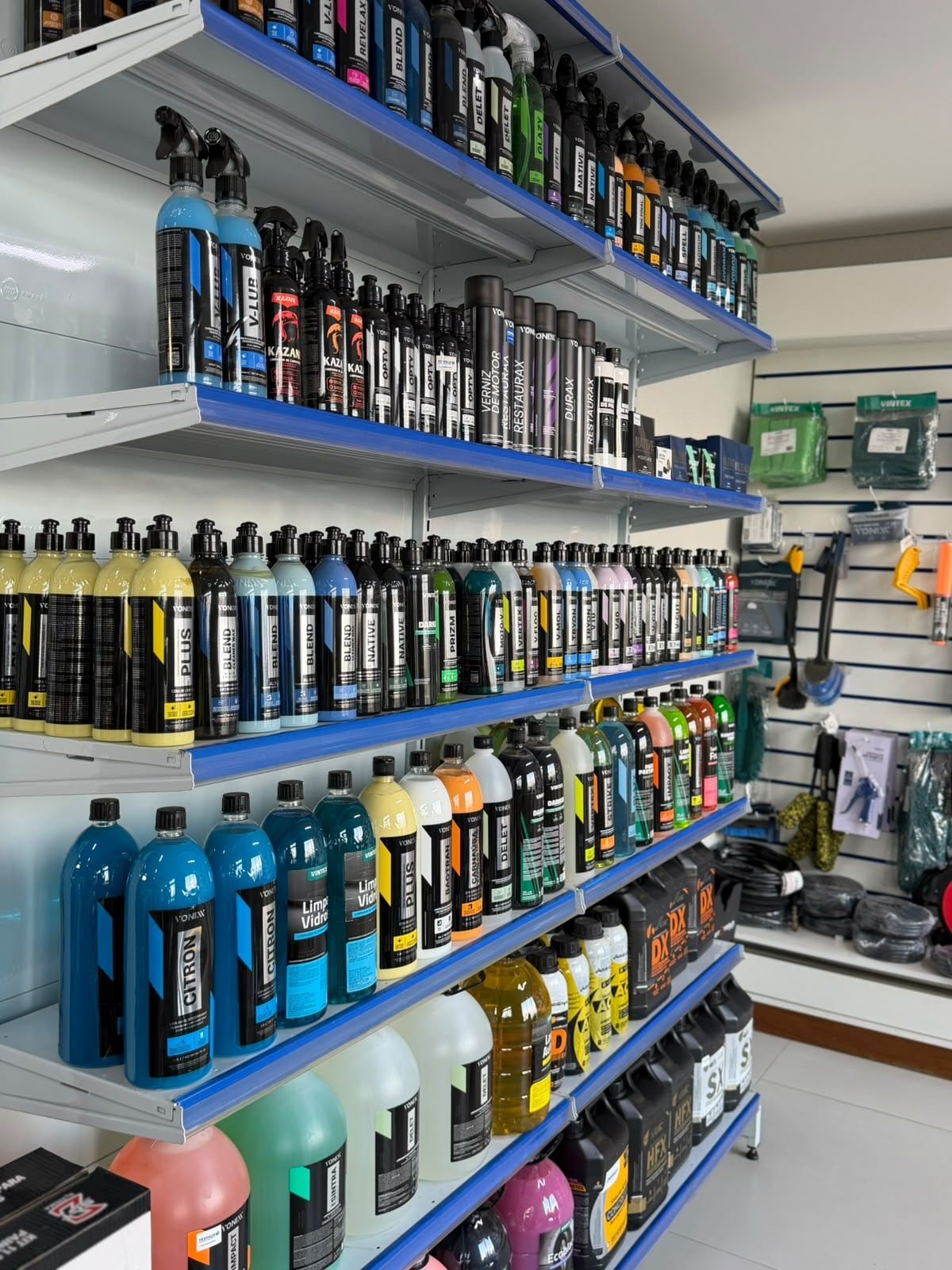 Estante com produtos de estética automotiva em frascos coloridos